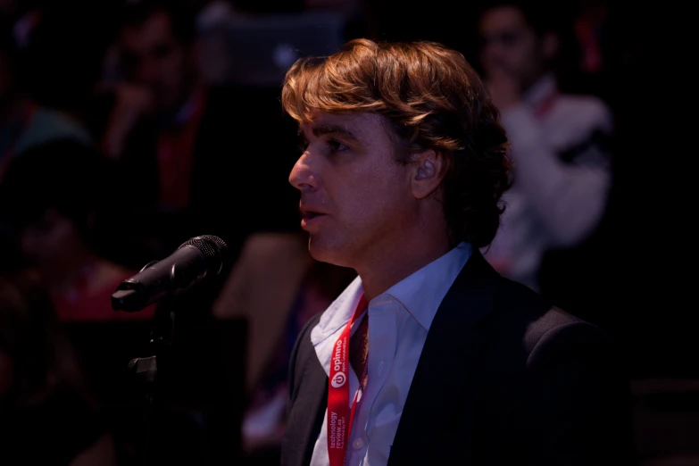 a young man in a suit speaking into a microphone