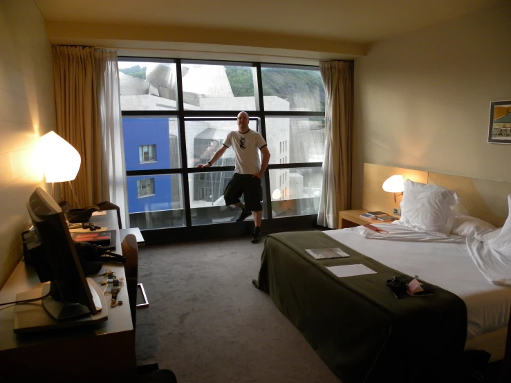 a man stands next to an open window in a room