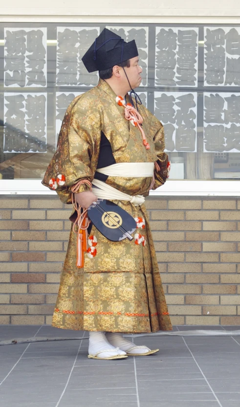 an asian man in traditional clothing looking out a window