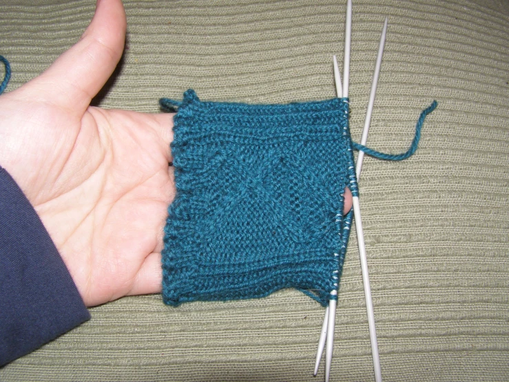 the hand is knitting on yarn with two needles