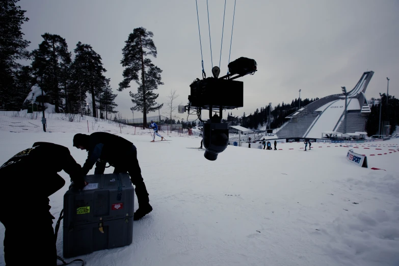 people stand in the snow next to a giant tv set