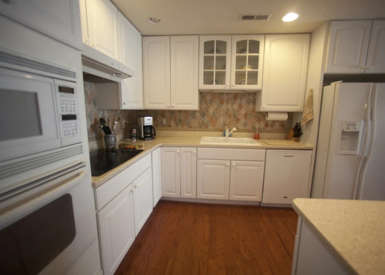 an empty kitchen that is white with white cabinets