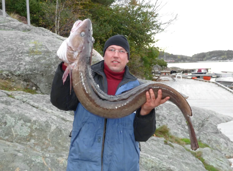 a man holding a large fish on top of a lake