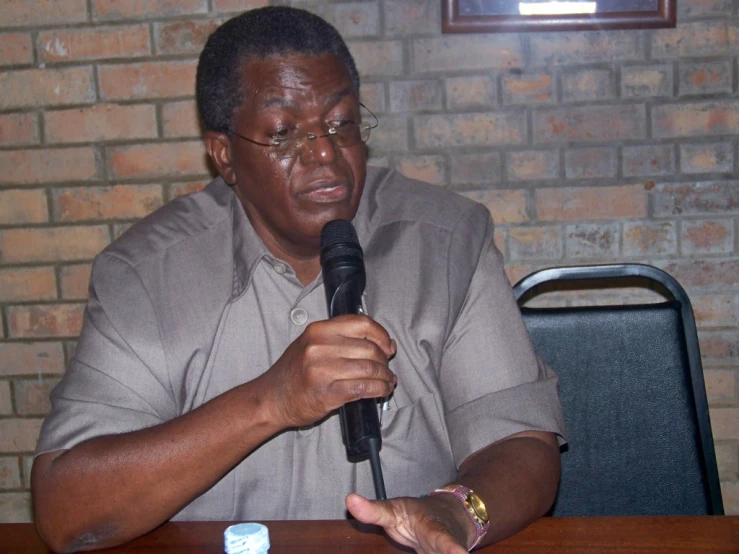 man in grey shirt holding up a microphone