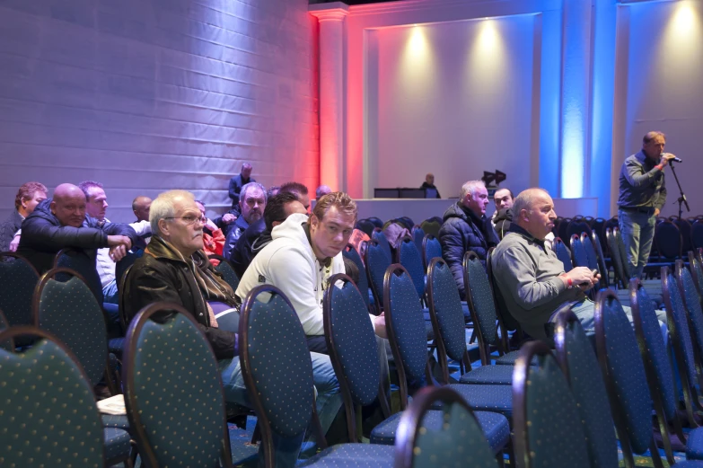 many people seated in rows with speakers on stage