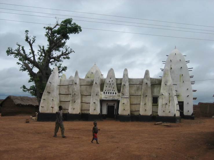 people walking around a desert area with an old structure