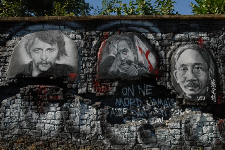 some graffiti on a brick wall with different portraits