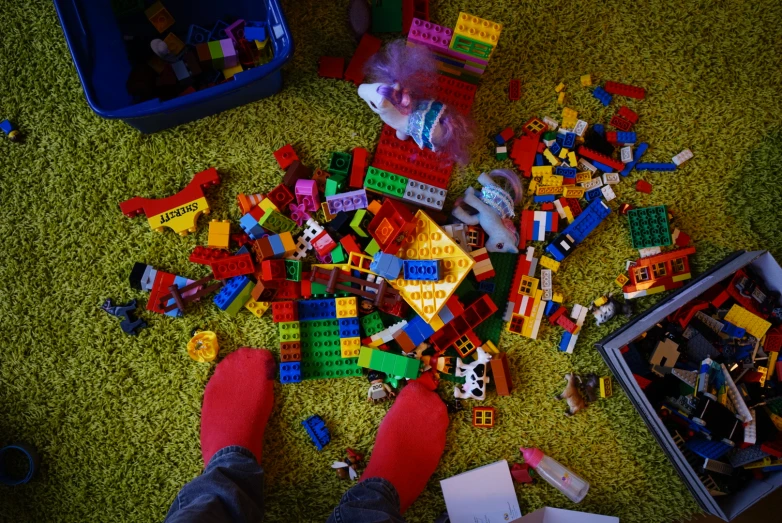 the man is laying down with a large amount of legos on the carpet