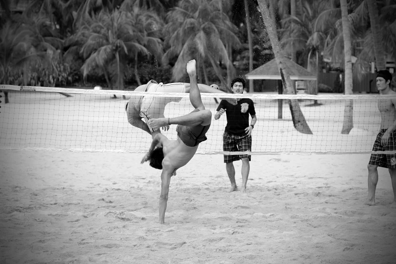 two men stand on their legs playing volleyball on the beach