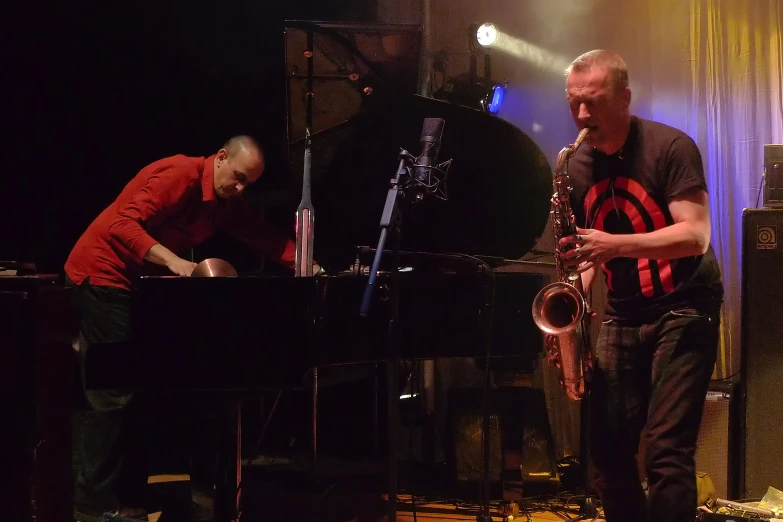 two men in red shirts playing on a piano