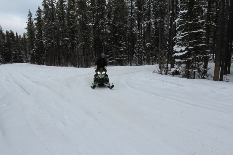 a man riding a snowmobile down a snow covered road