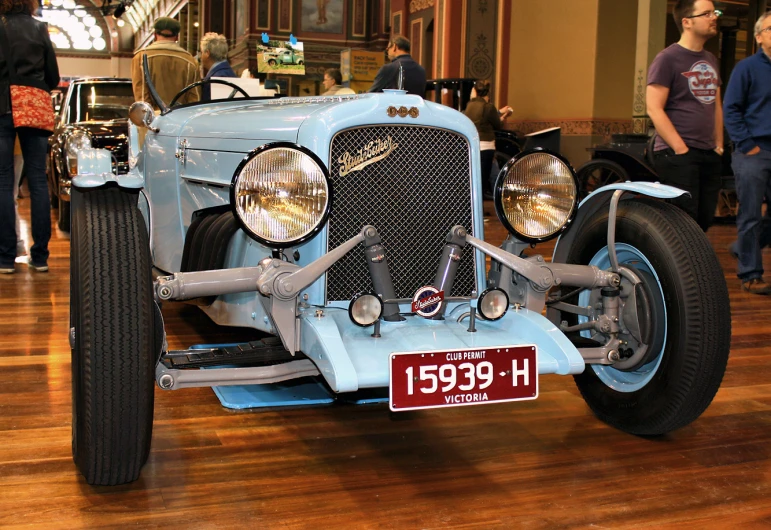 an old fashioned blue car sitting on a wooden floor