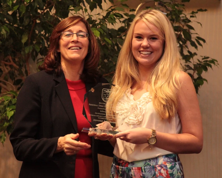 two women posing together with an award