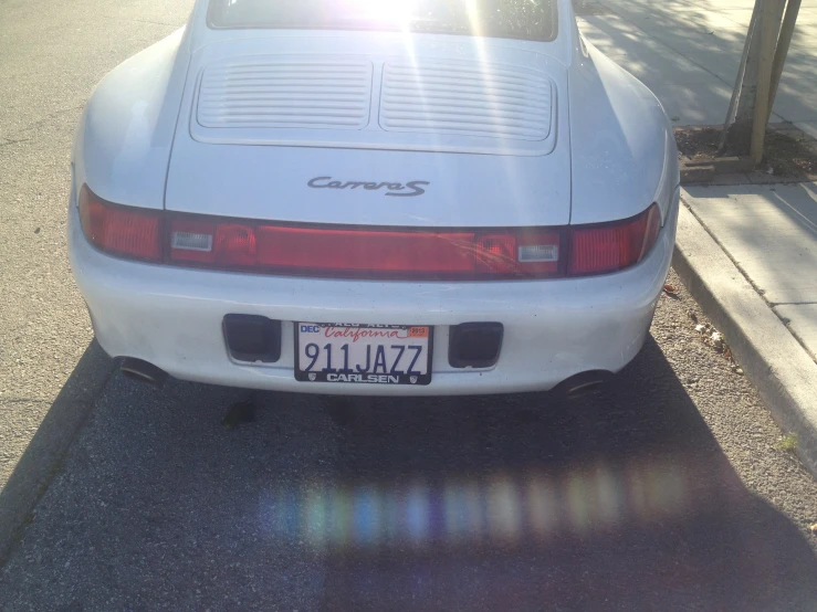 the rear of an older, white sports car parked on the street