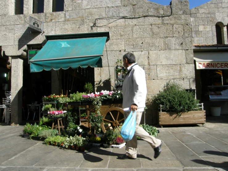 a man walking past flowers and flowershelves on a street