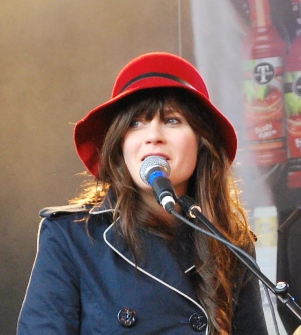a girl with a red hat on singing into a microphone