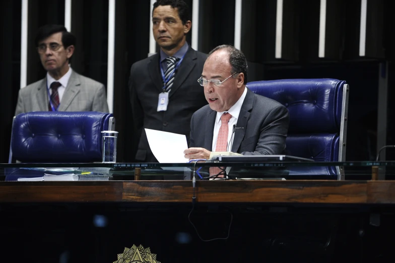 a man reading a piece of paper in front of two other men