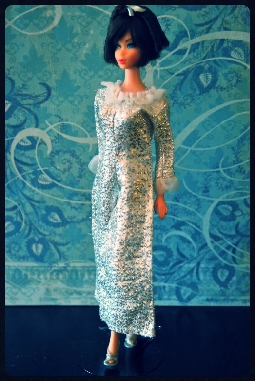 a barbie doll wearing an evening dress on a black surface