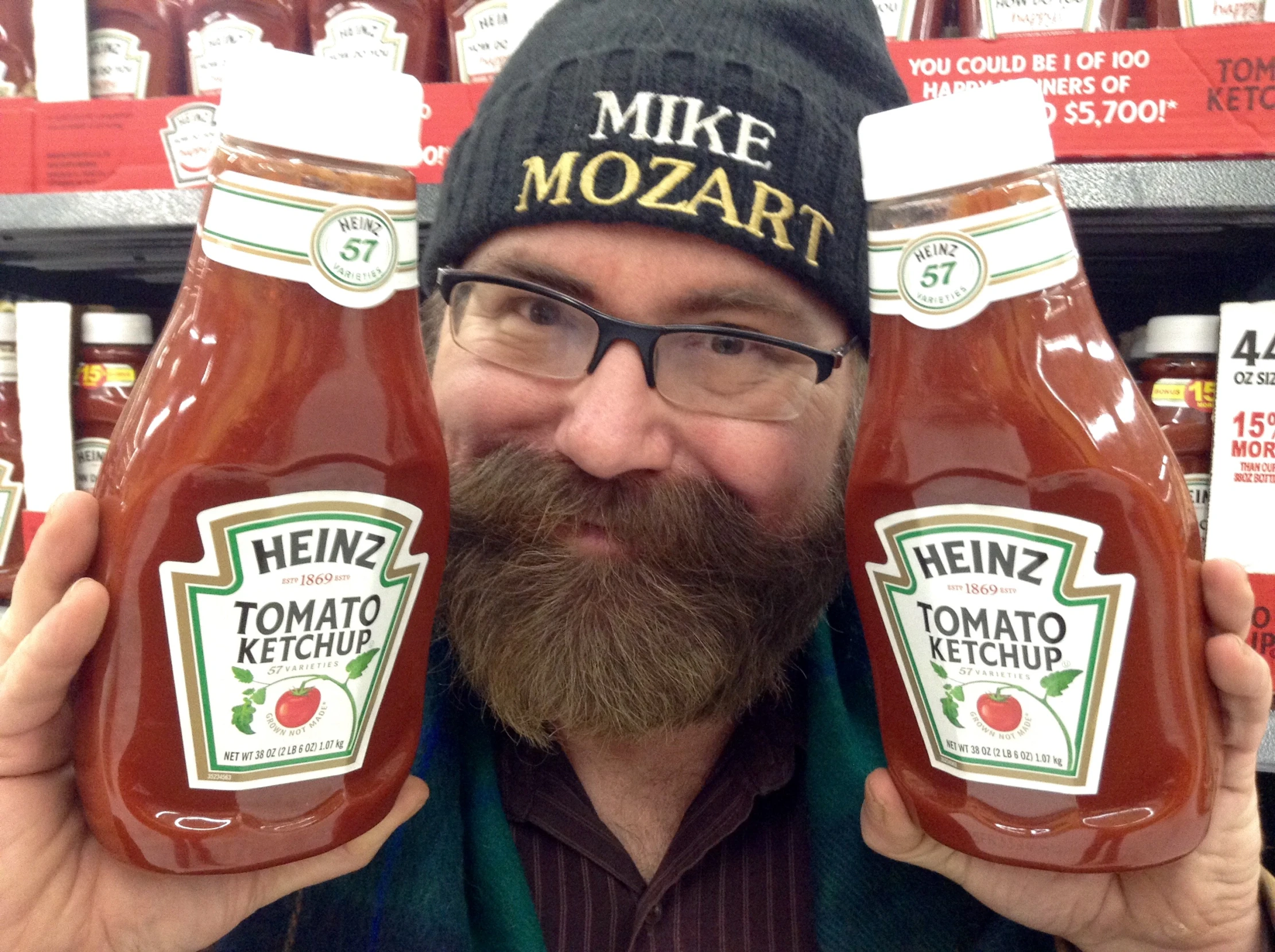 a man standing inside a store holding two jars of heinz's tomato ketchup