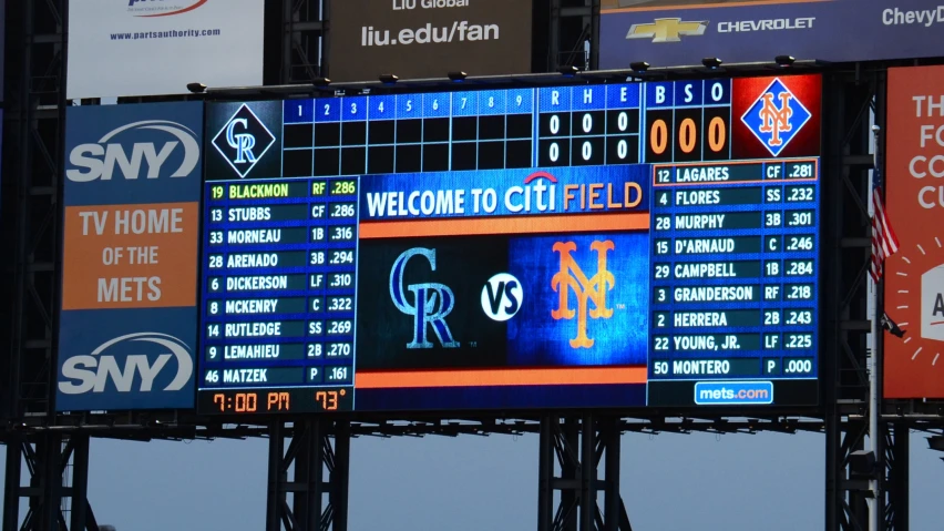 a baseball stadium score board with multiple teams in the back