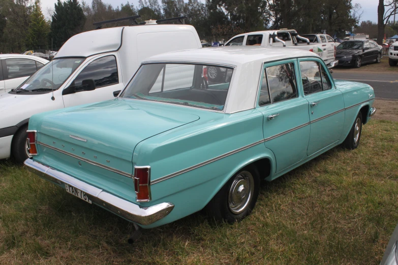 an older blue car is sitting in the grass