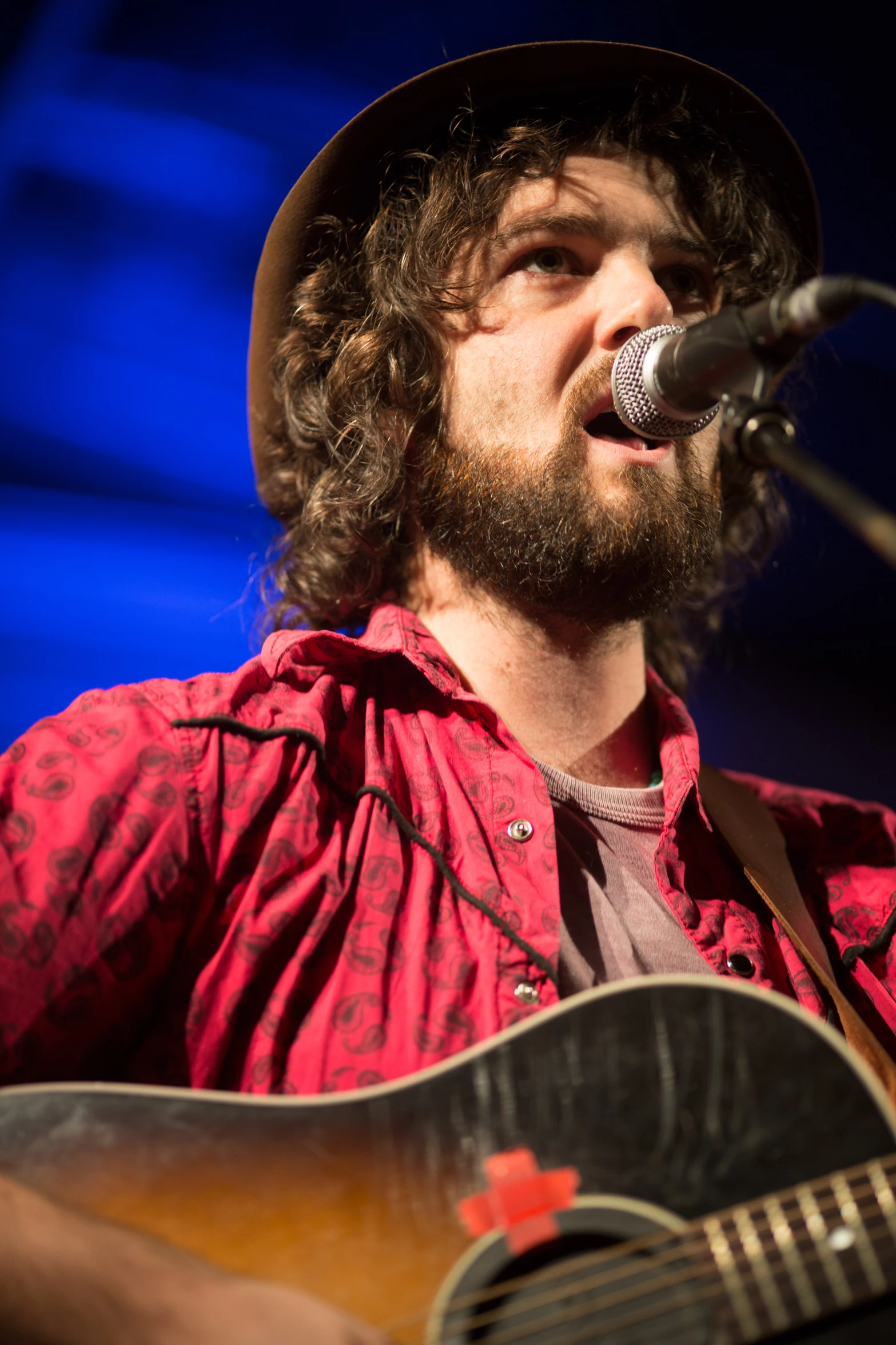 a person with a guitar and singing into a microphone