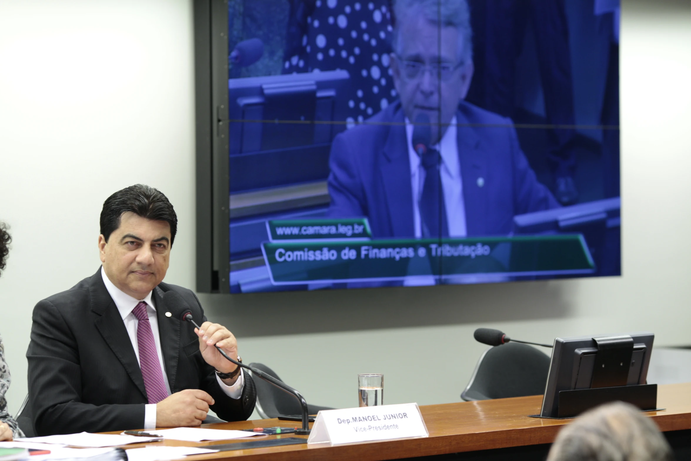 a man sitting at a table while talking in front of a television