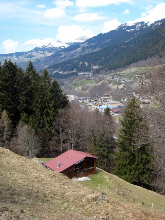 a red roofed building sits in the background of the mountains