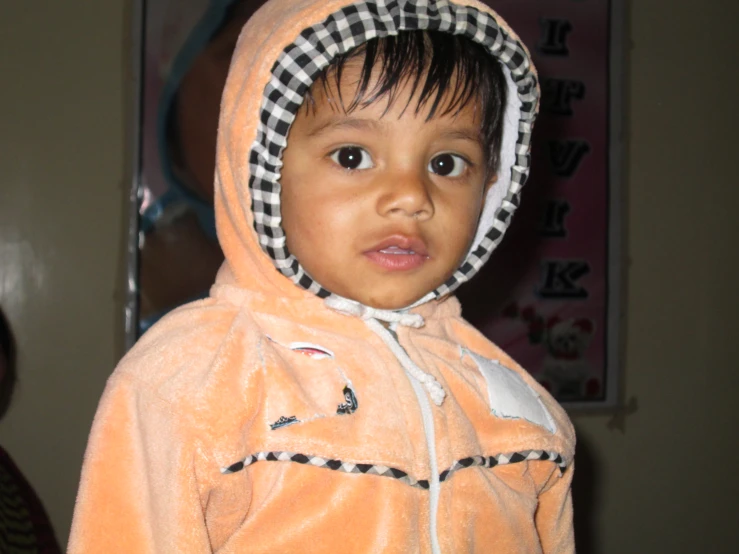 a small child wearing a pink colored hooded jacket
