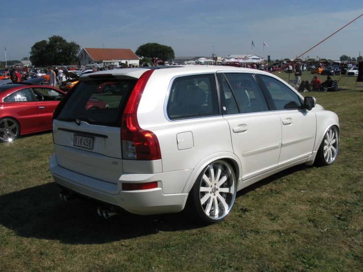 the rear end of a white car parked in the grass