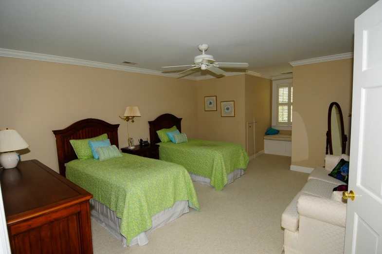 a bedroom has two beds and a ceiling fan