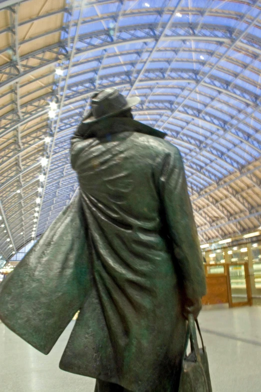 a statue in an indoor train station, holding a purse