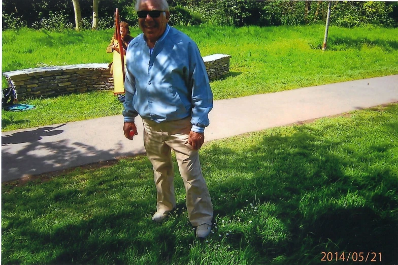man posing in grass in front of a walkway
