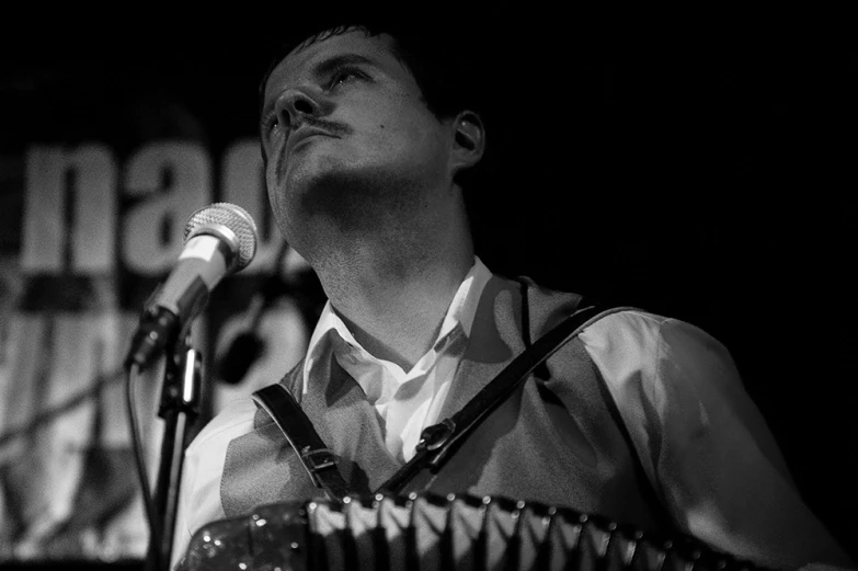 a man standing behind a microphone with his eyes closed