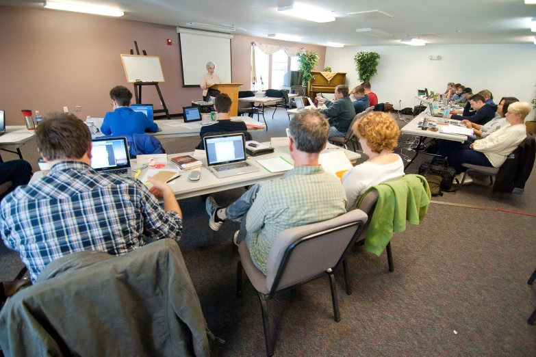 a group of people at tables and laptops with their computers