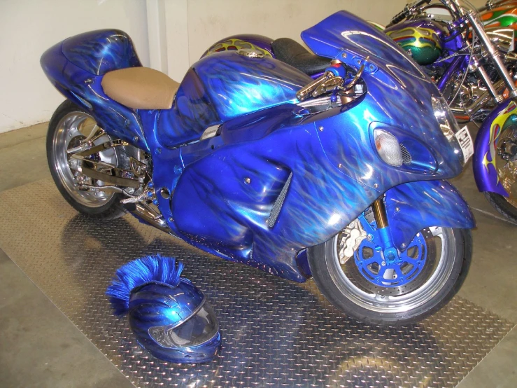 blue motorcycle parked in a room surrounded by other motorcycles