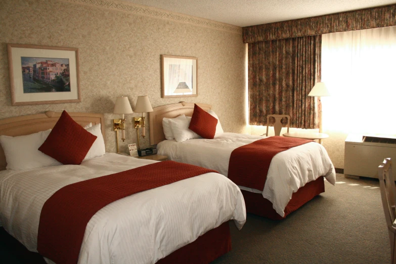 two beds with matching blankets and red pillows