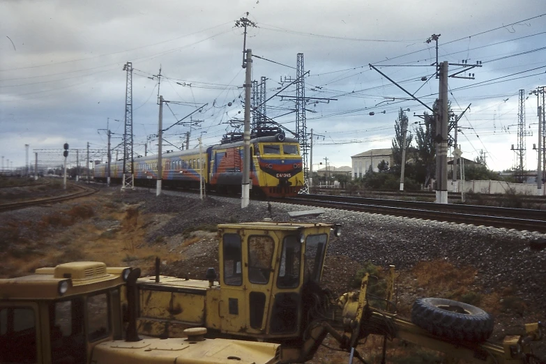 a yellow train is driving by a pile of old machinery