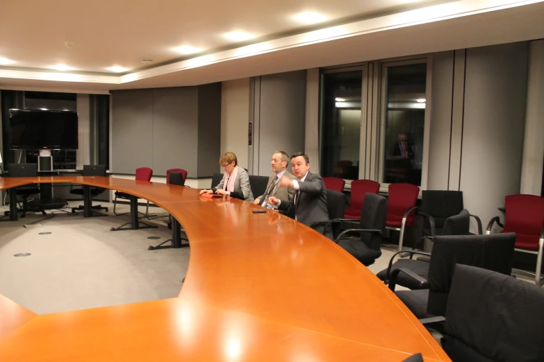 a large long desk in an office with three men in chairs