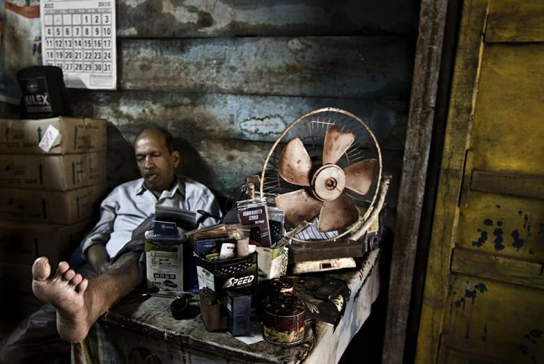 the man is sitting near his small desk