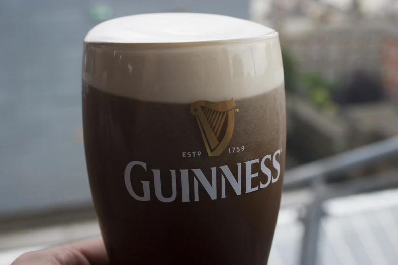 someone is holding a guinness glass for the camera