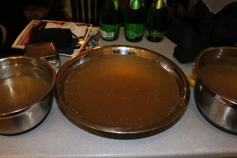 some brown liquid in a metallic pan and two drinks