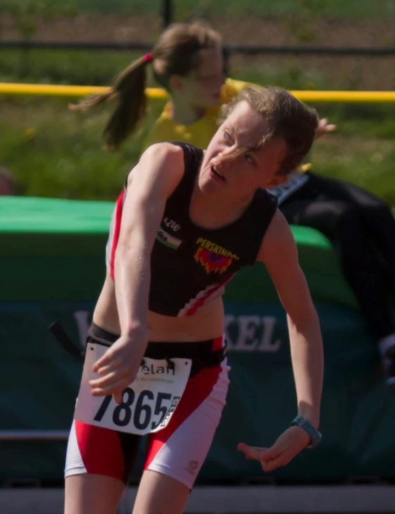 a girl is running in a competition with her hands to the side