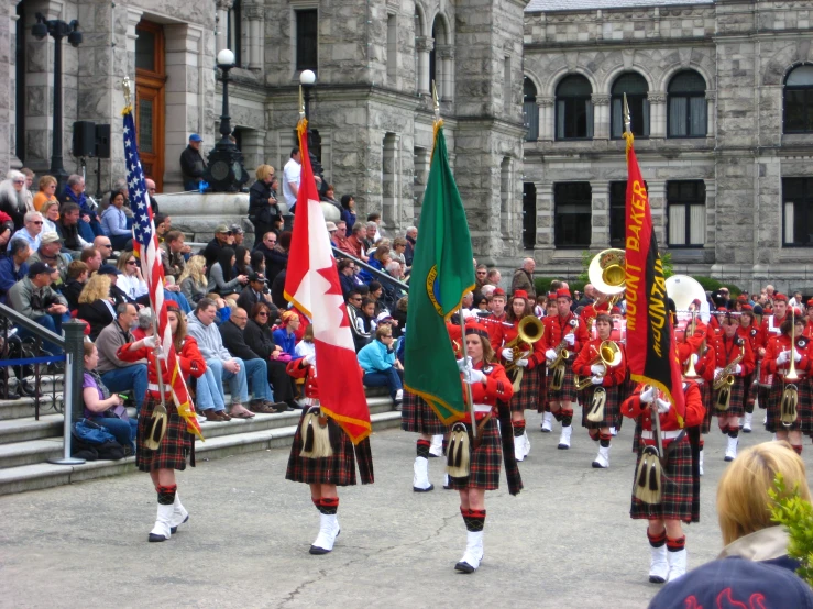 some people in dress clothes and flags standing near a building