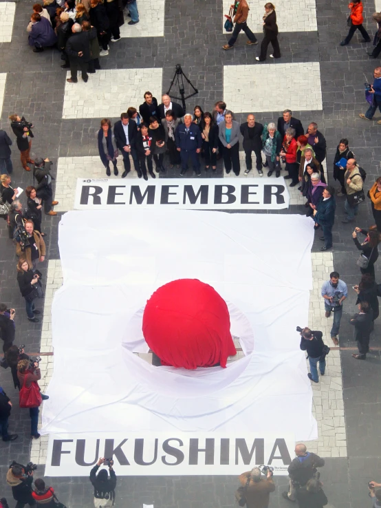 large white sign with red design on it surrounded by many people