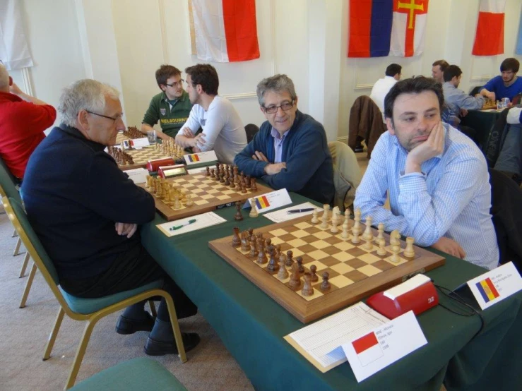 people are sitting at a table with chess boards