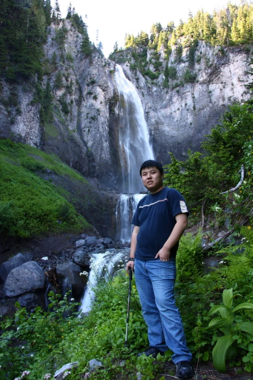 a man is standing next to a waterfall and a stream