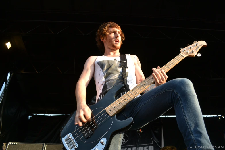 young man in white shirt with guitar necker attached playing