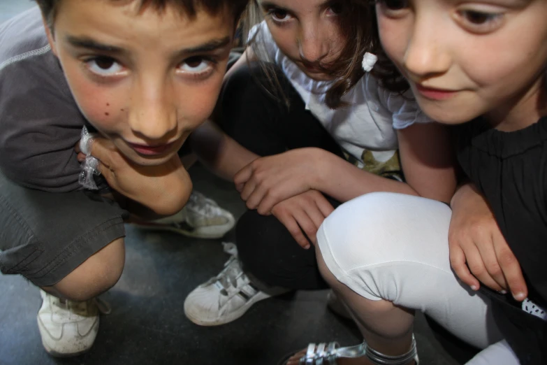 three young children with their mouths open and one leaning over a little boy