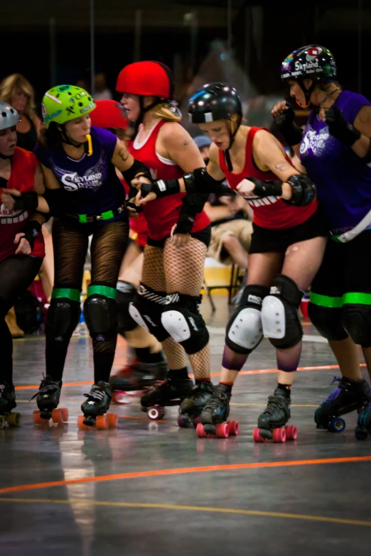 some women in short skirt and red tops rollerblading on a track